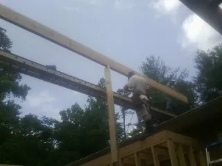 Carpenter setting a ridge beam over a new addition frame — Ice Dam Removal by Roofing Brothers in Saint James