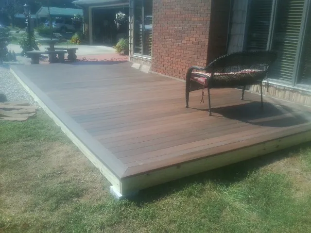 New wood deck and wicker chair beside a brick house in Saint James
