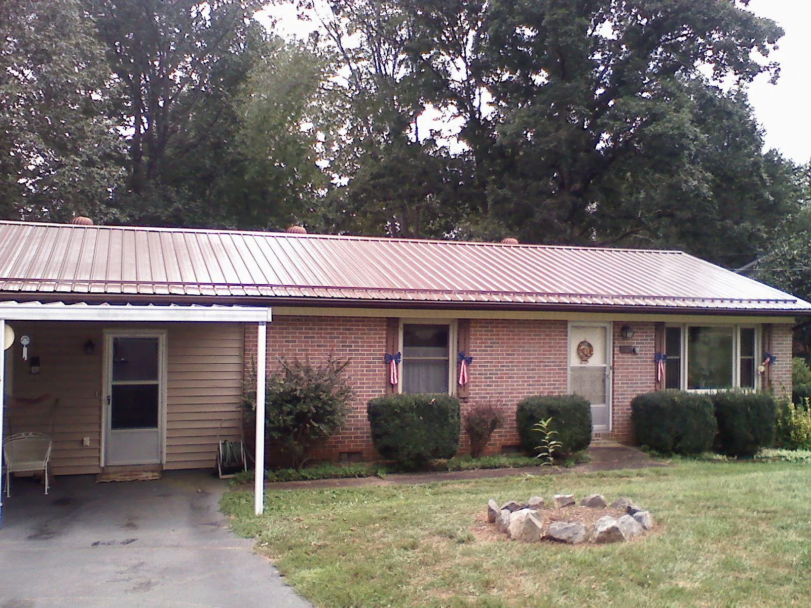 Bronze metal roof and carport on a brick ranch home — Roof Repair work by our crew in Saint James