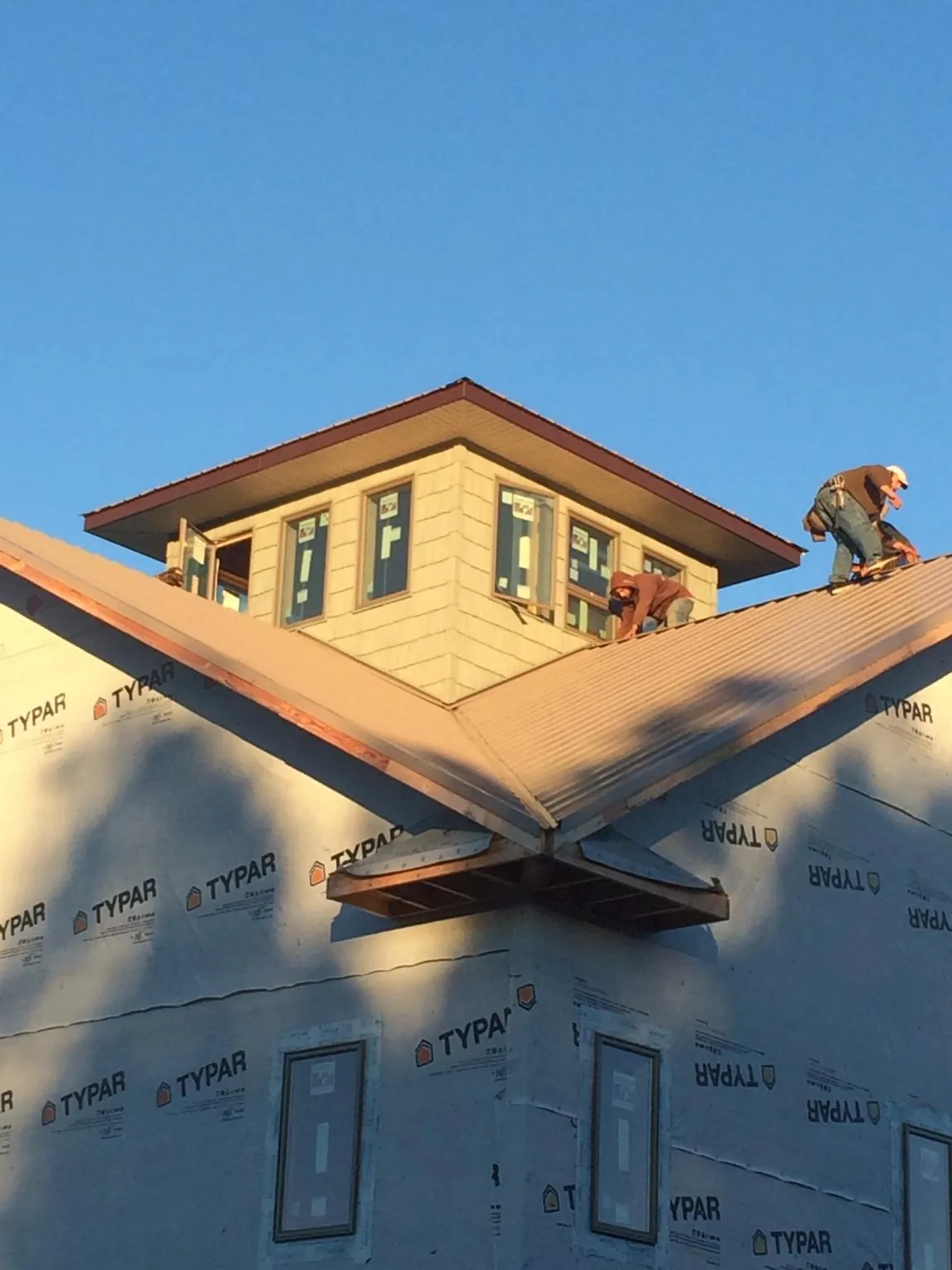 Roofers working around a rooftop cupola on a new metal roof at sunset — Roof Waterproofing in Saint James by Roofing Brothers